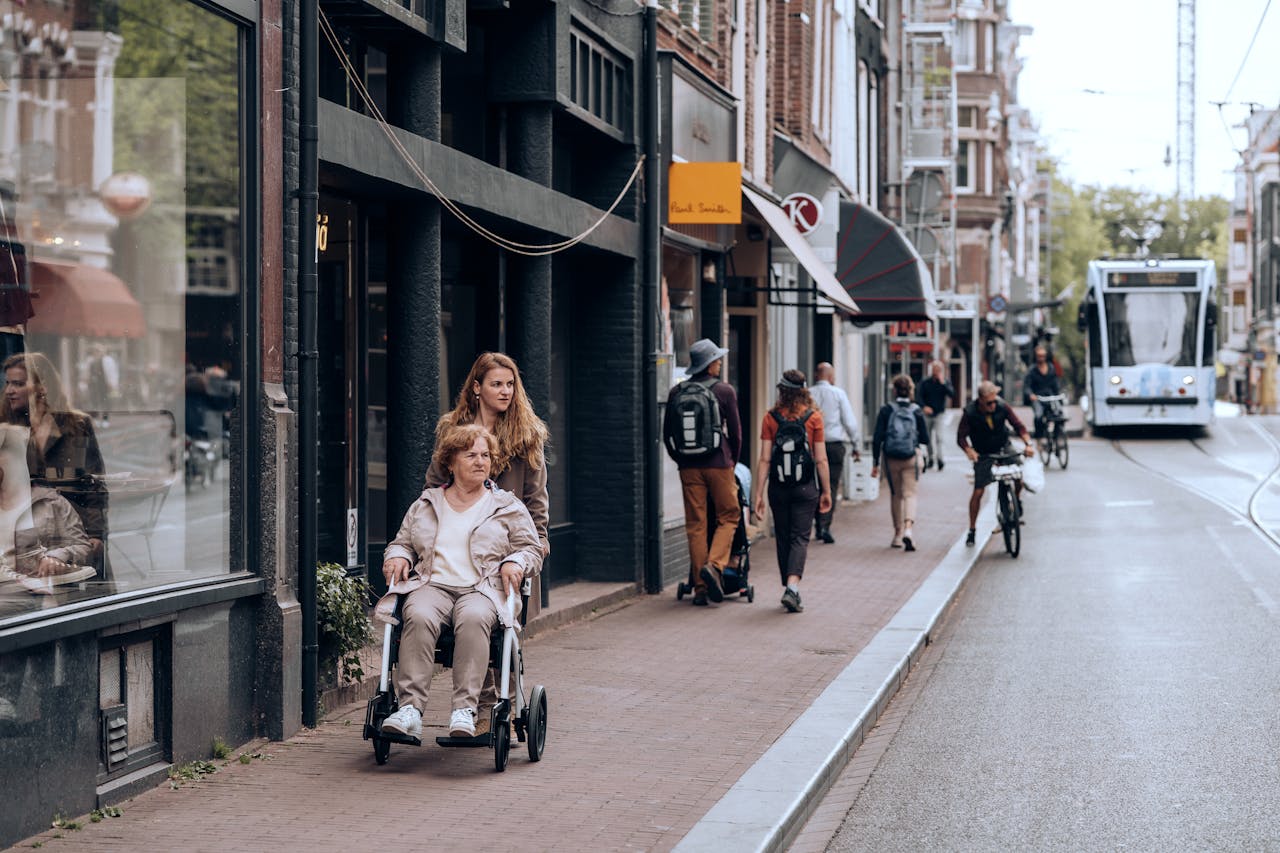 gallery-6 Street view in Amsterdam with people using mobility aids and bikes, reflecting urban life.