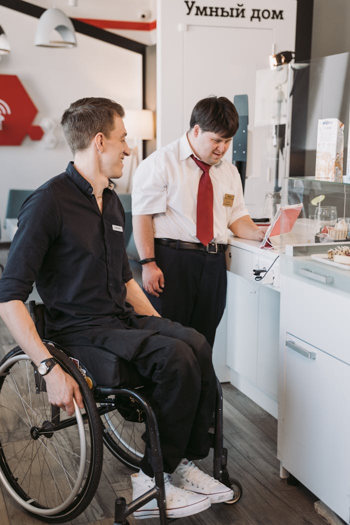Two men in an office showcasing inclusivity with technology use. One is sitting in a wheelchair.