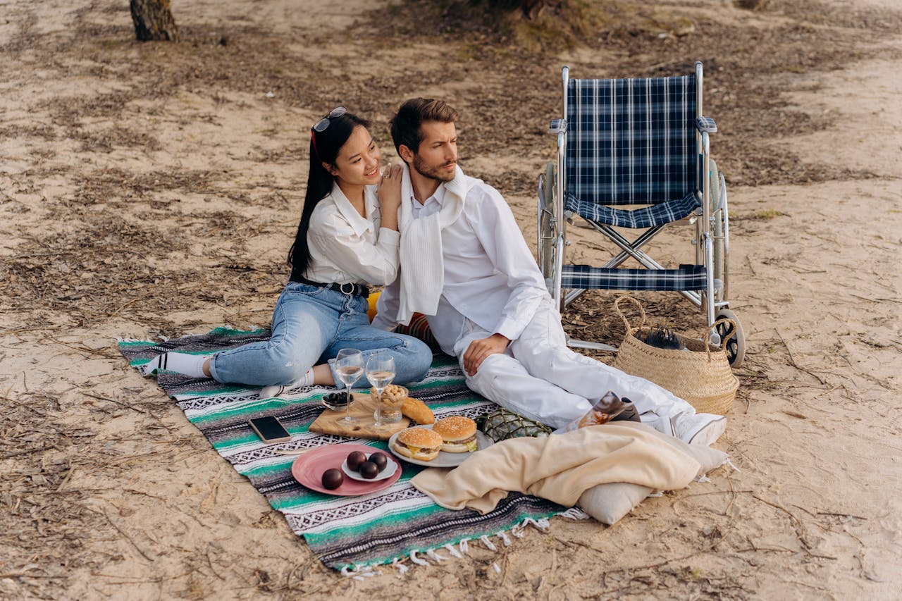 services-04 A couple enjoys a romantic picnic on the beach, including a wheelchair for accessibility.